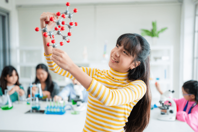 A student holding up a model of a molecule in a science lab